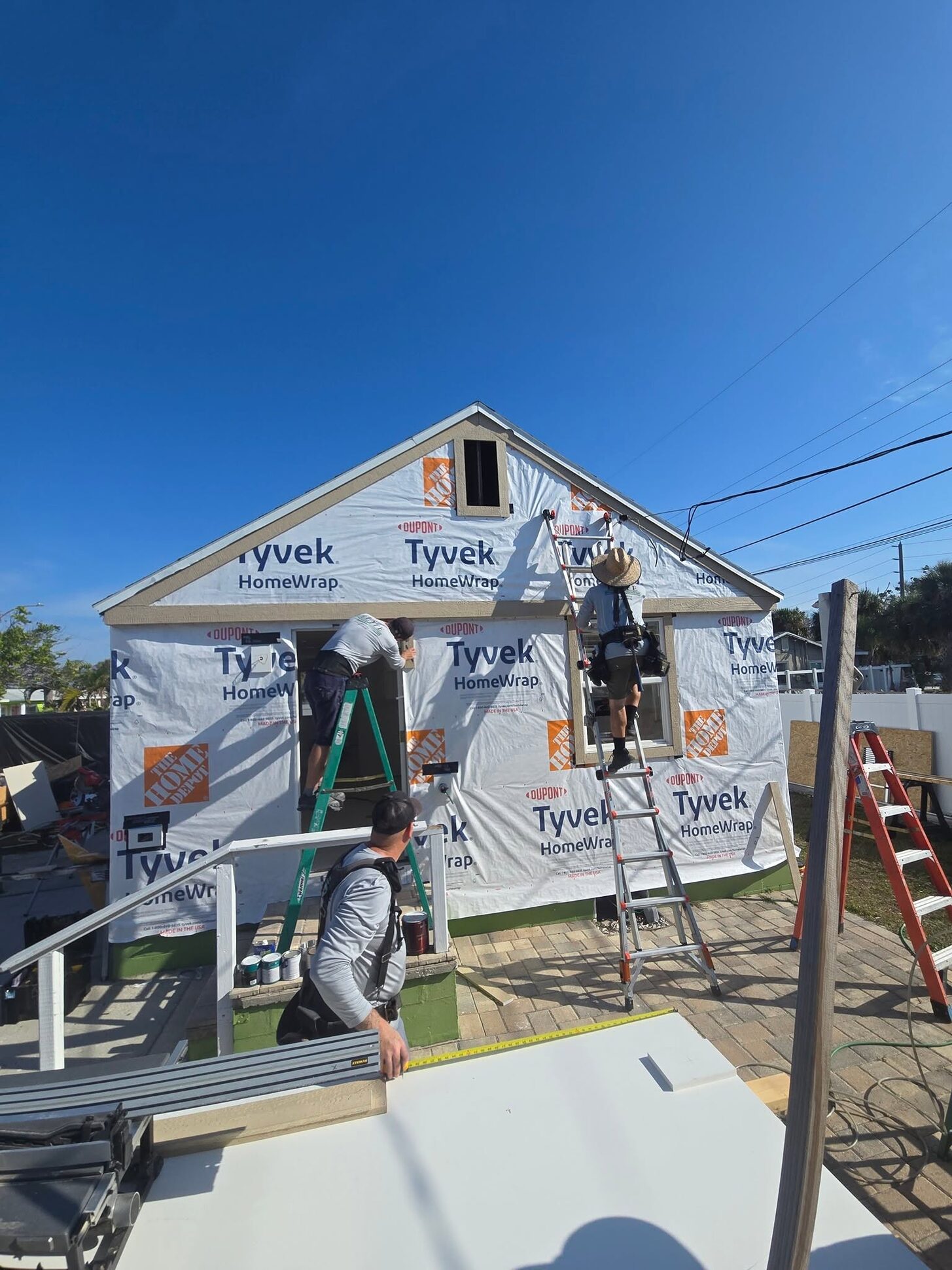 Isla Breeze in house wrap with the Reliant crew on ladders during the flood rebuild