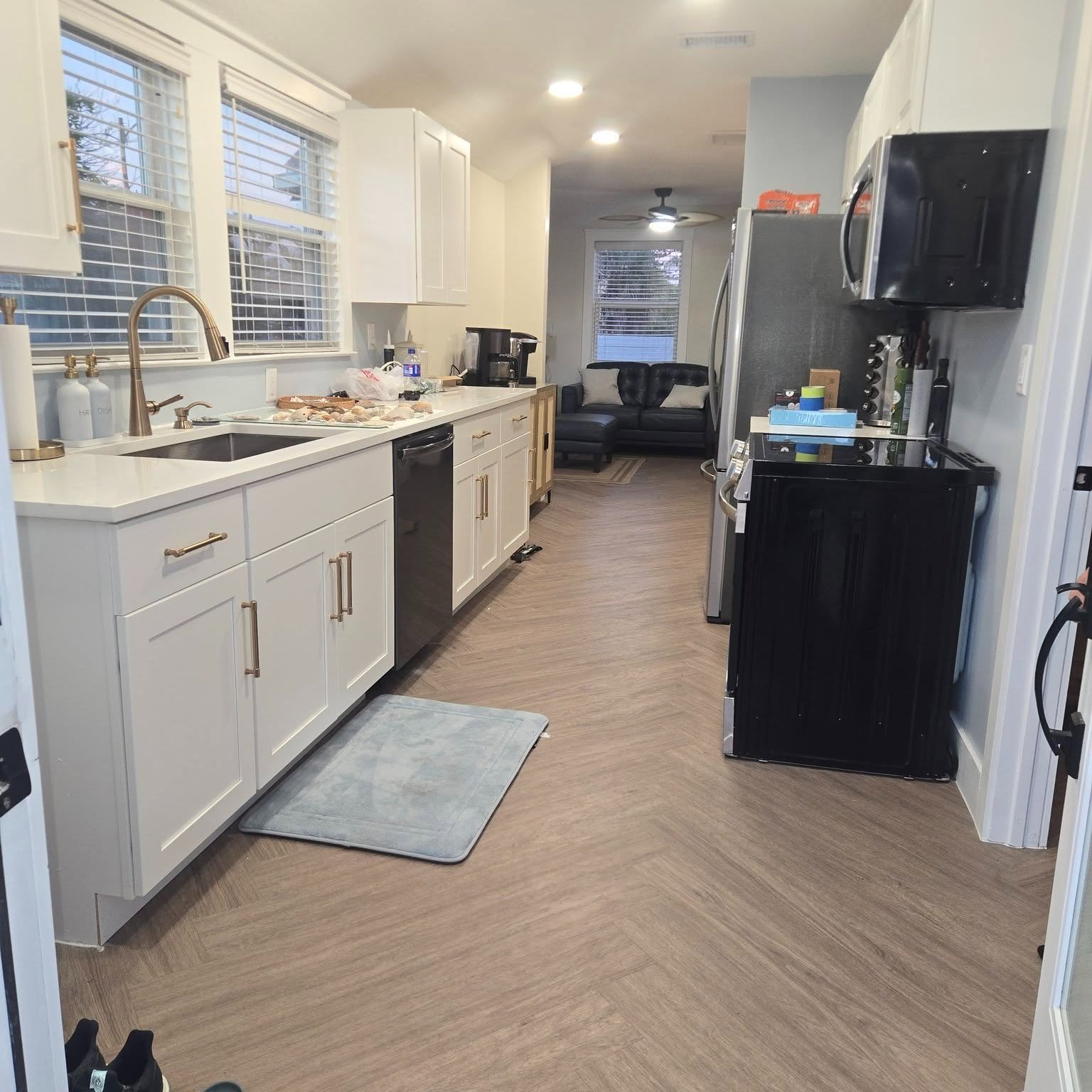 A white open-plan galley kitchen with herringbone flooring after a Reliant remodel