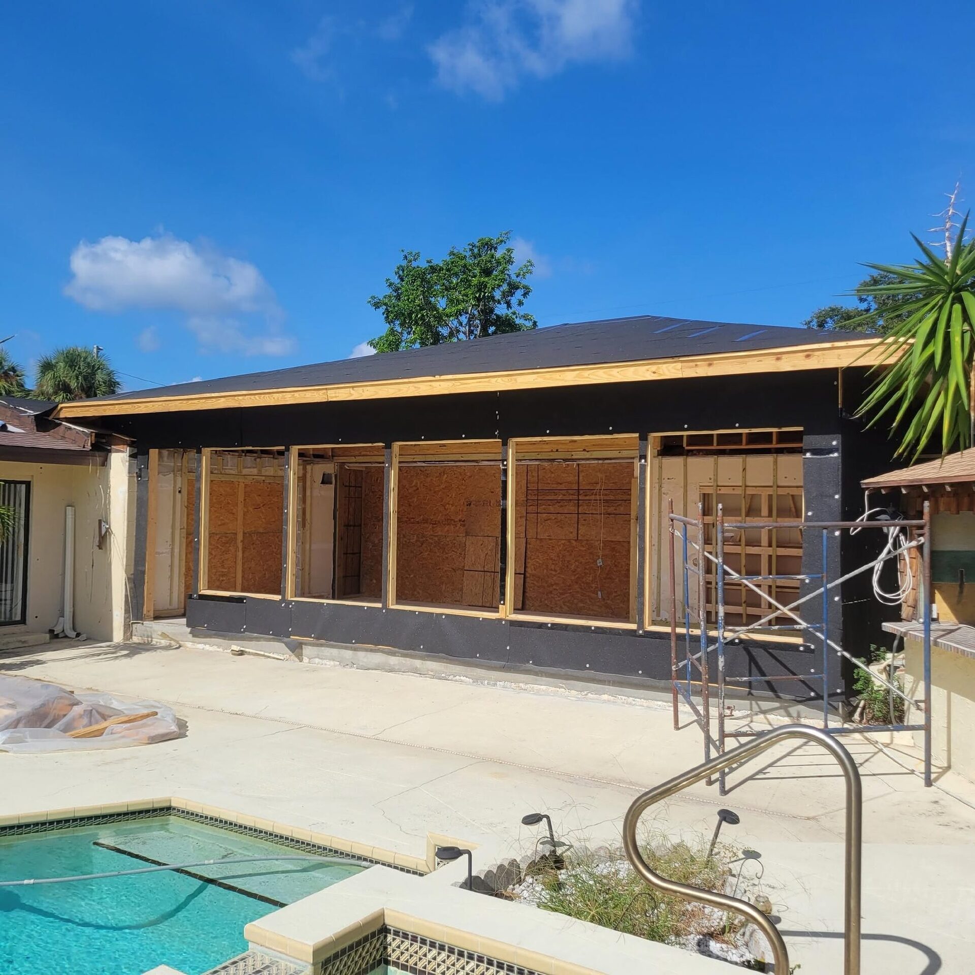 A pool-lanai enclosure addition in framing under a blue sky, a Reliant Service Team job