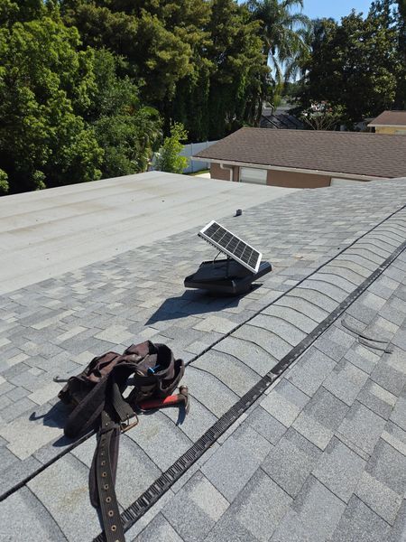 A tool belt resting on new shingles at a ridge vent on a Reliant roof