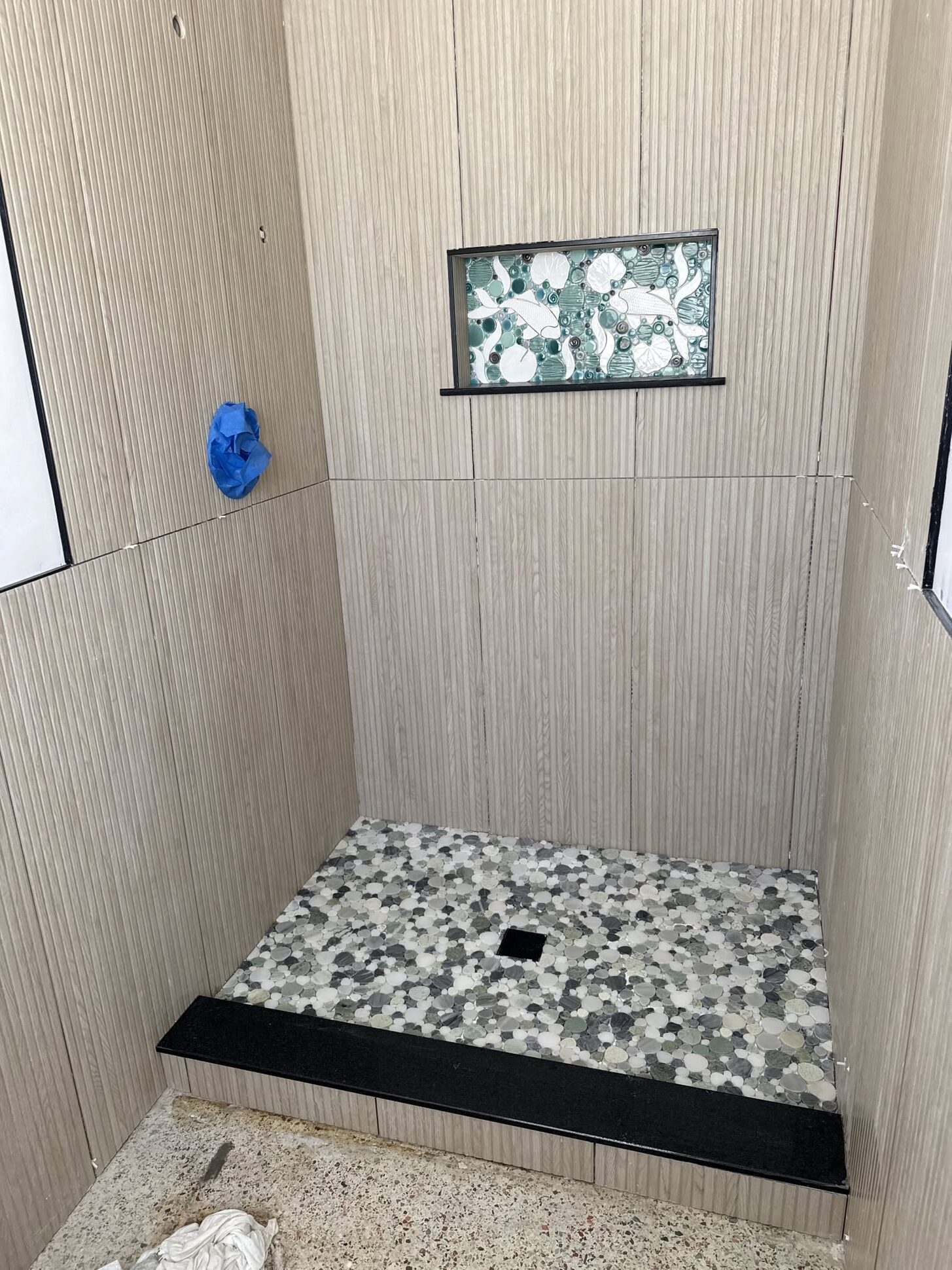 A pebble shower floor and tiled niche in a Reliant bathroom remodel