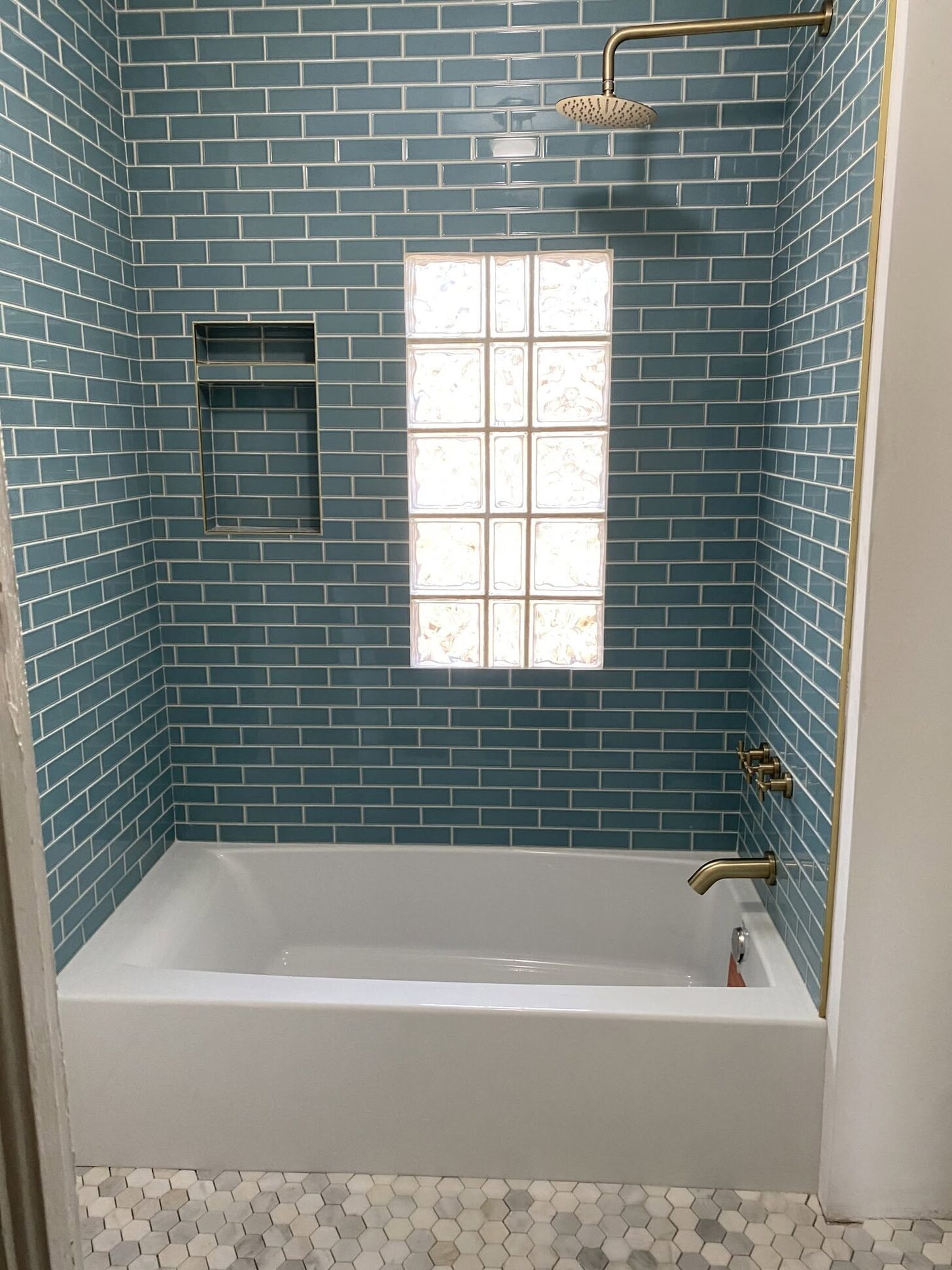 A teal subway-tile tub surround with a glass-block window, remodeled by Reliant Service Team